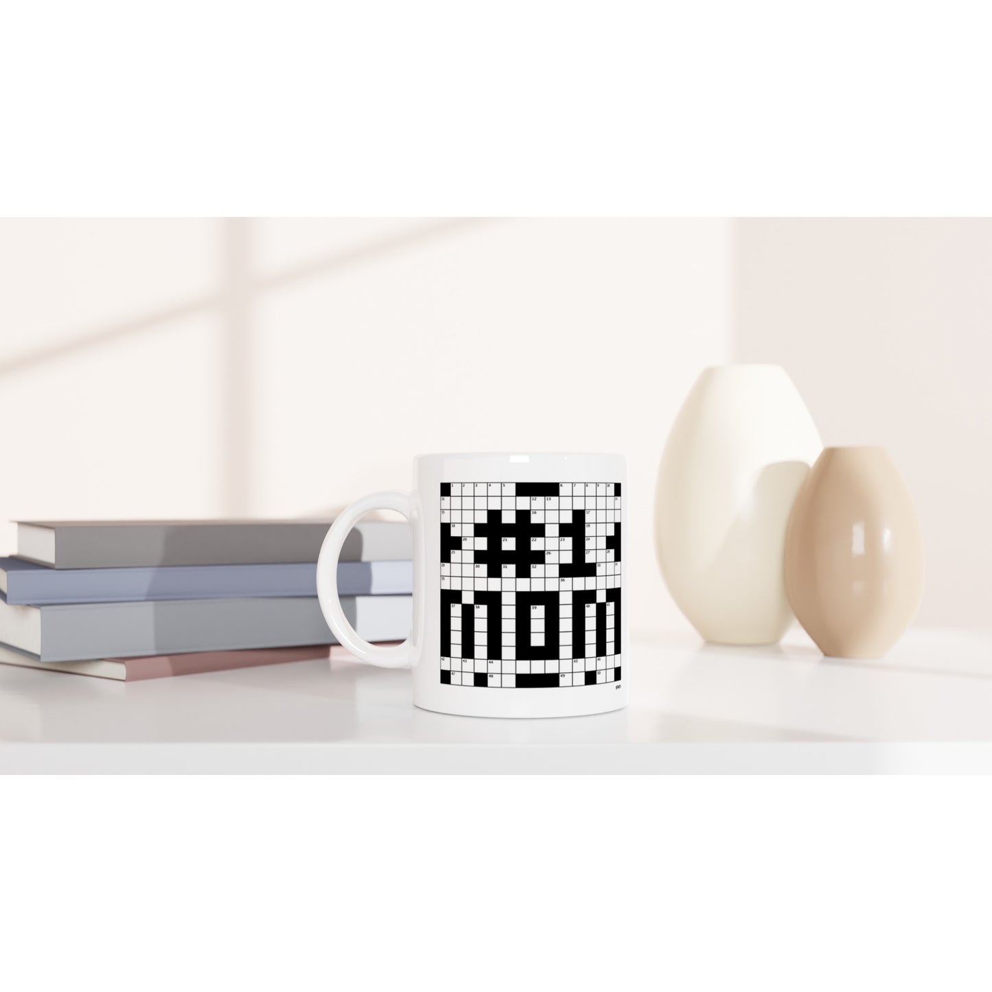 A white, ceramic mug with a crossword puzzle themed graphic that reads #1 MOM sits on a coffee table.