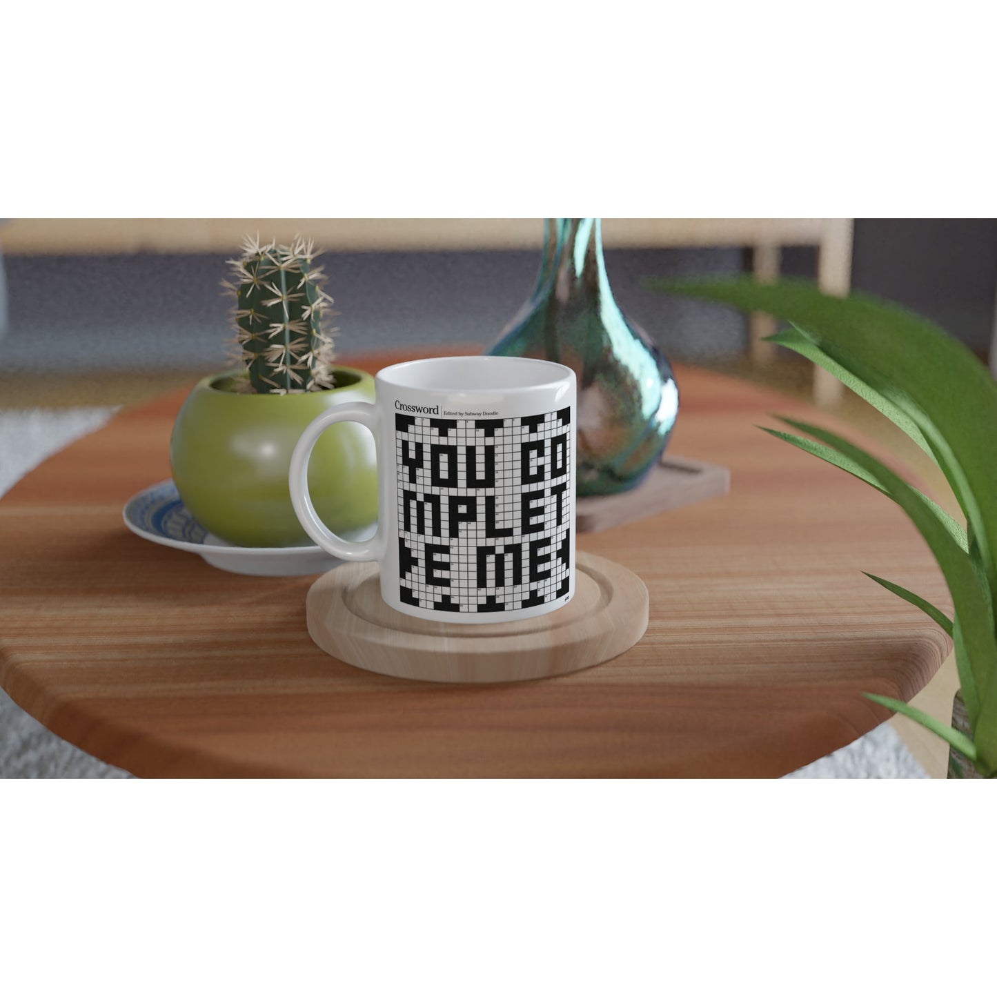 A white coffee or tea mug with a crossword themed graphic that reads YOU COMPLETE ME on an end table.